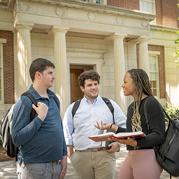three students talking in front of the law school